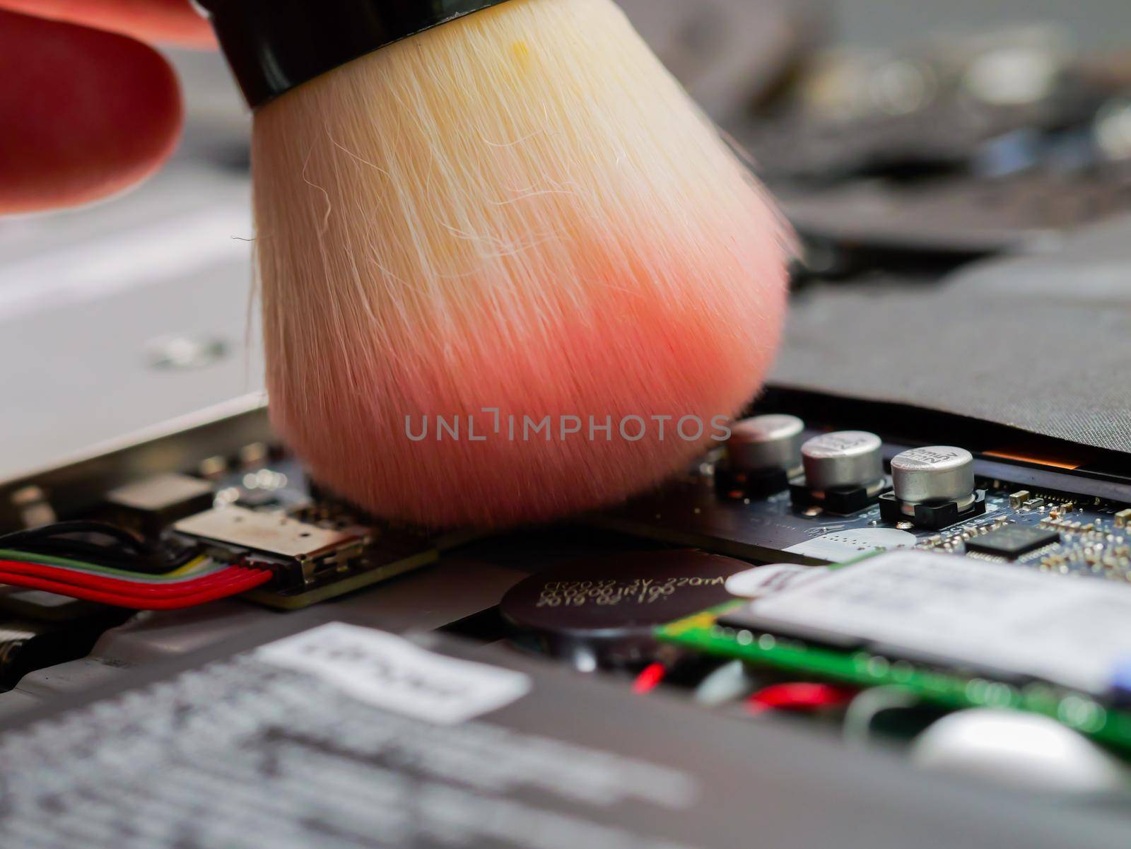 Cleaning a laptop with brush at a professional service. by RecCameraStock