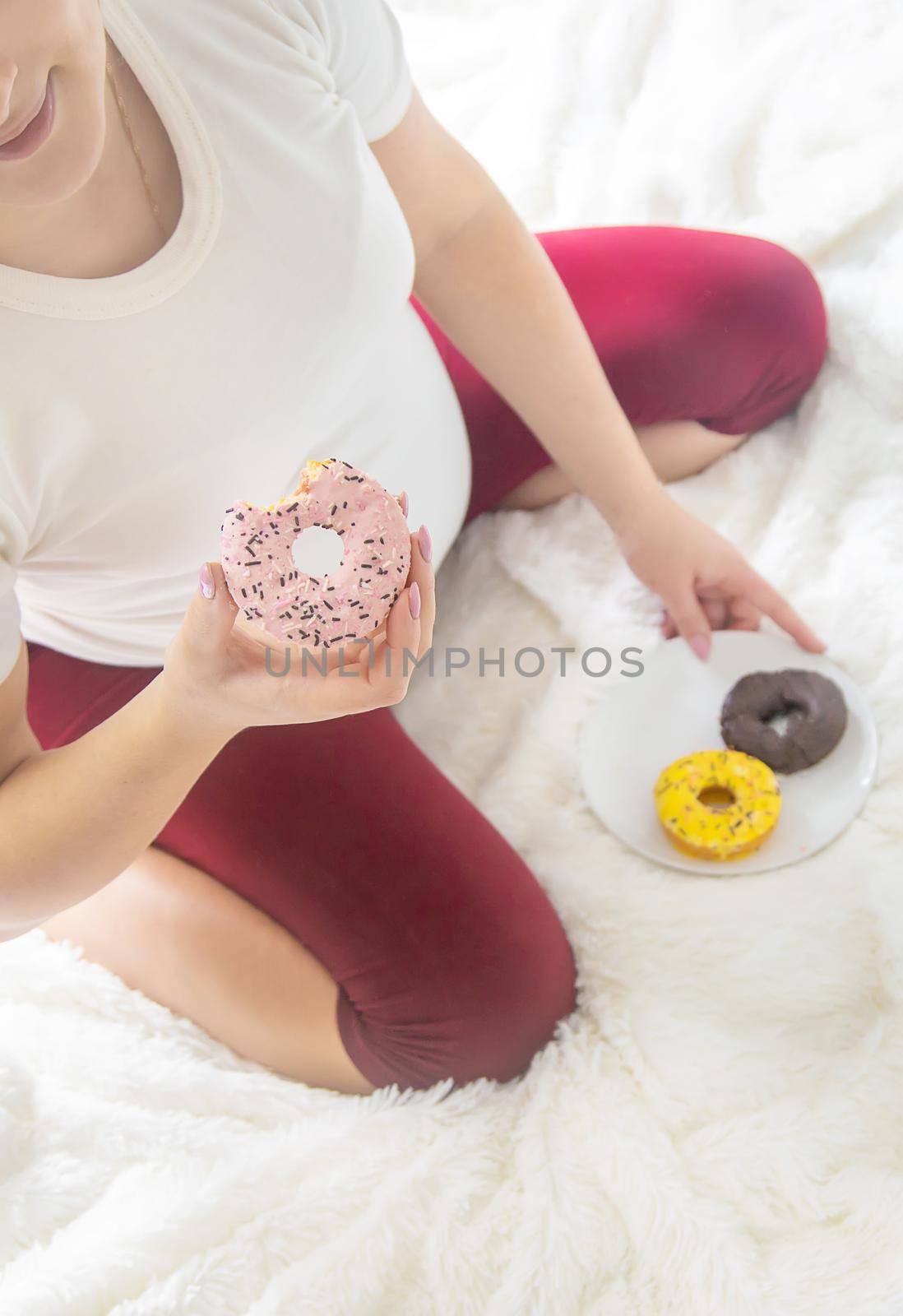 A pregnant woman eats sweet donuts. Selective Focus. Food.