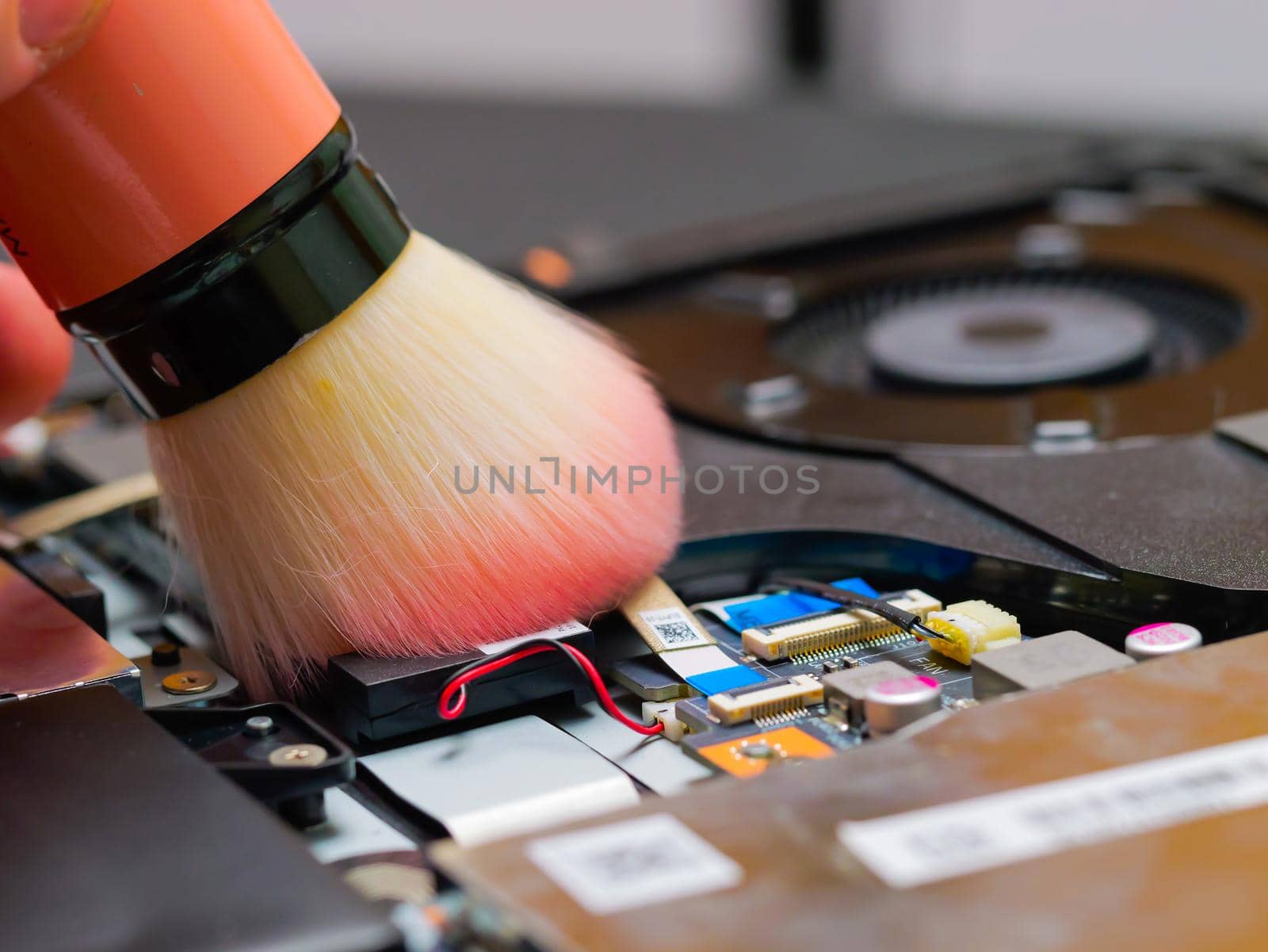 Macro of a brush cleaning a laptop motherboard. Cleaning a laptop removing the dust with big brush.
