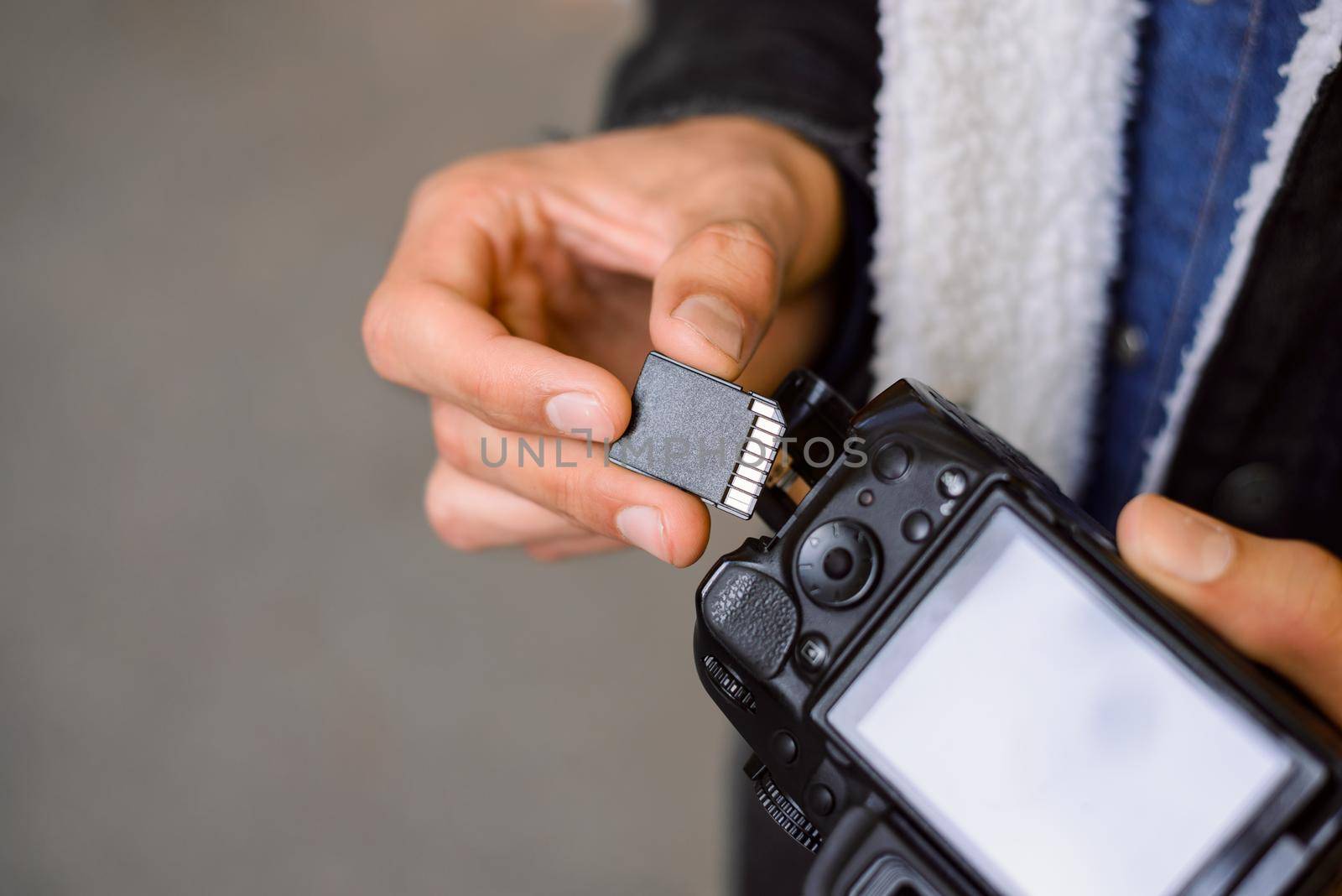 Hand of photographer holding SD memory Card. Male photographer changing SD card of a photo camera outdoors