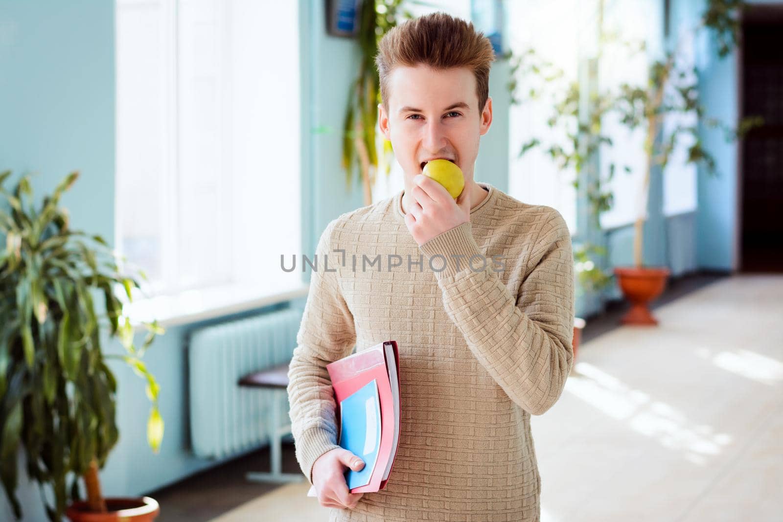 Happy male student eating an apple by VitaliiPetrushenko