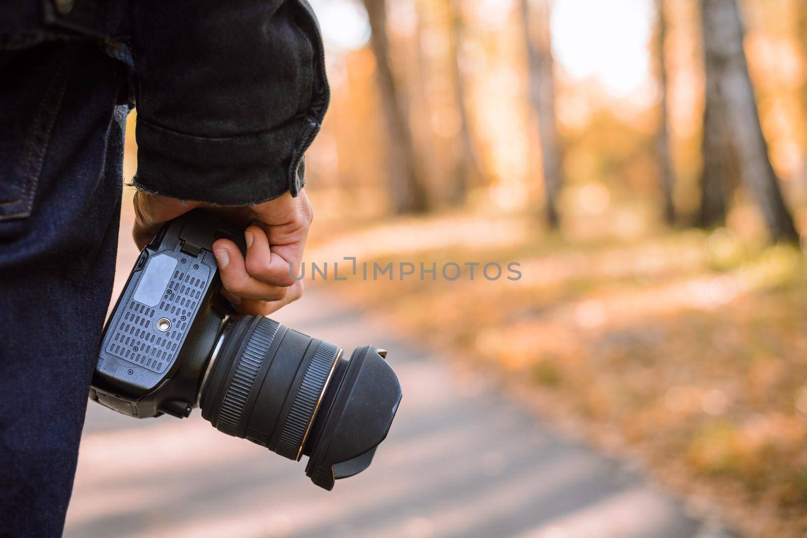 Nature photographer with digital camera going to shoot some landscapes in autumn forest in the evening