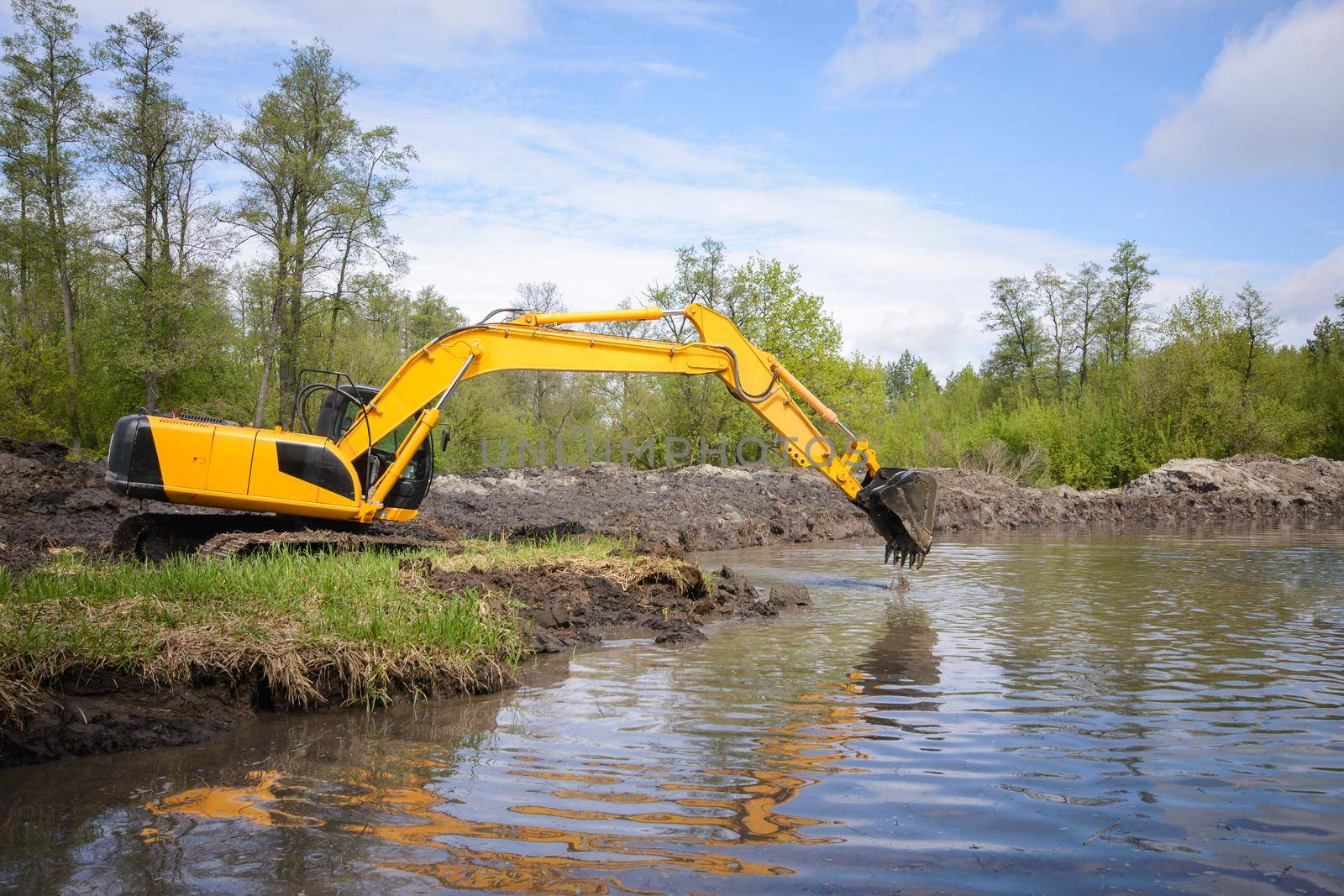 Excavator near small river or pond in countryside by VitaliiPetrushenko