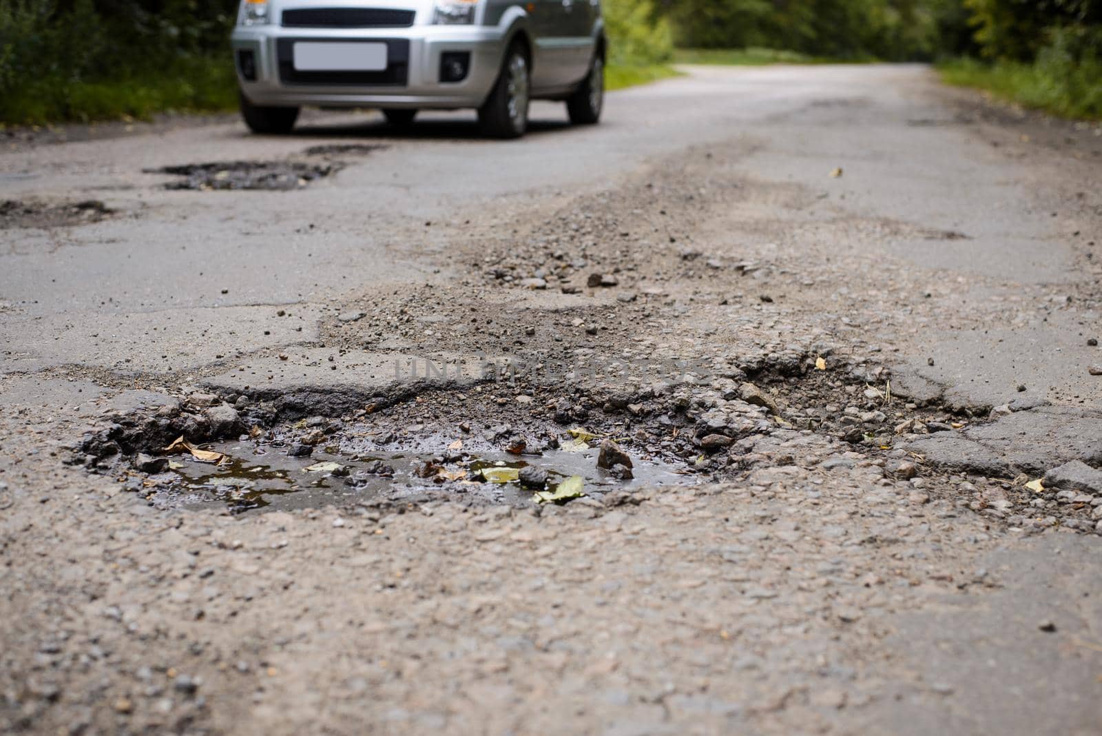 Damaged asphalt pavement road with many big and deep potholes by VitaliiPetrushenko