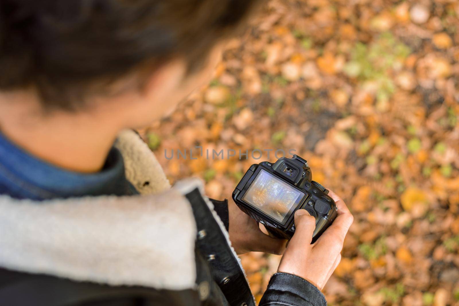 Photographer standing with camera in autumn forest with yellow and orange foliage on the background