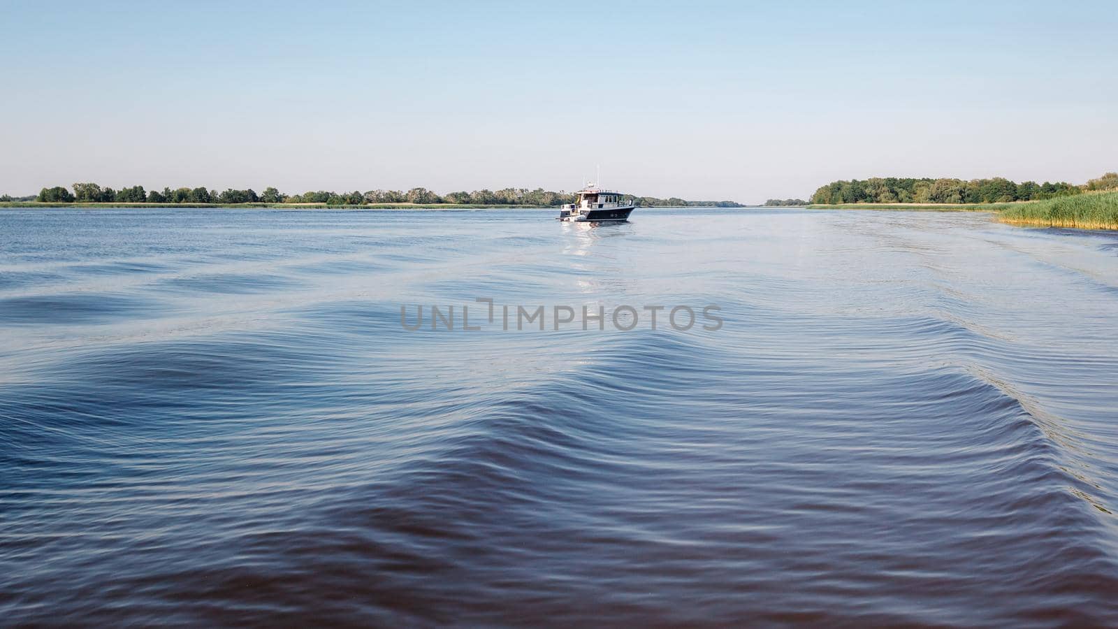 A large and wide rippling water and a small boat in the distance in the lagoon