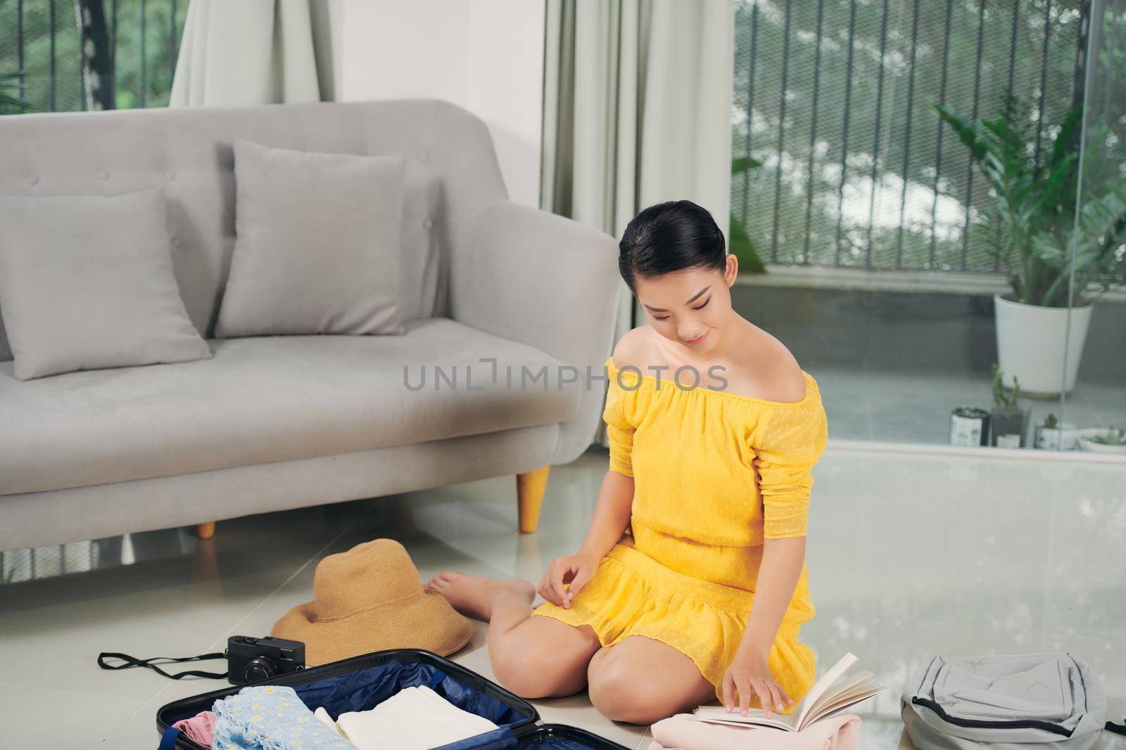 happy young woman packing travel bag at home 