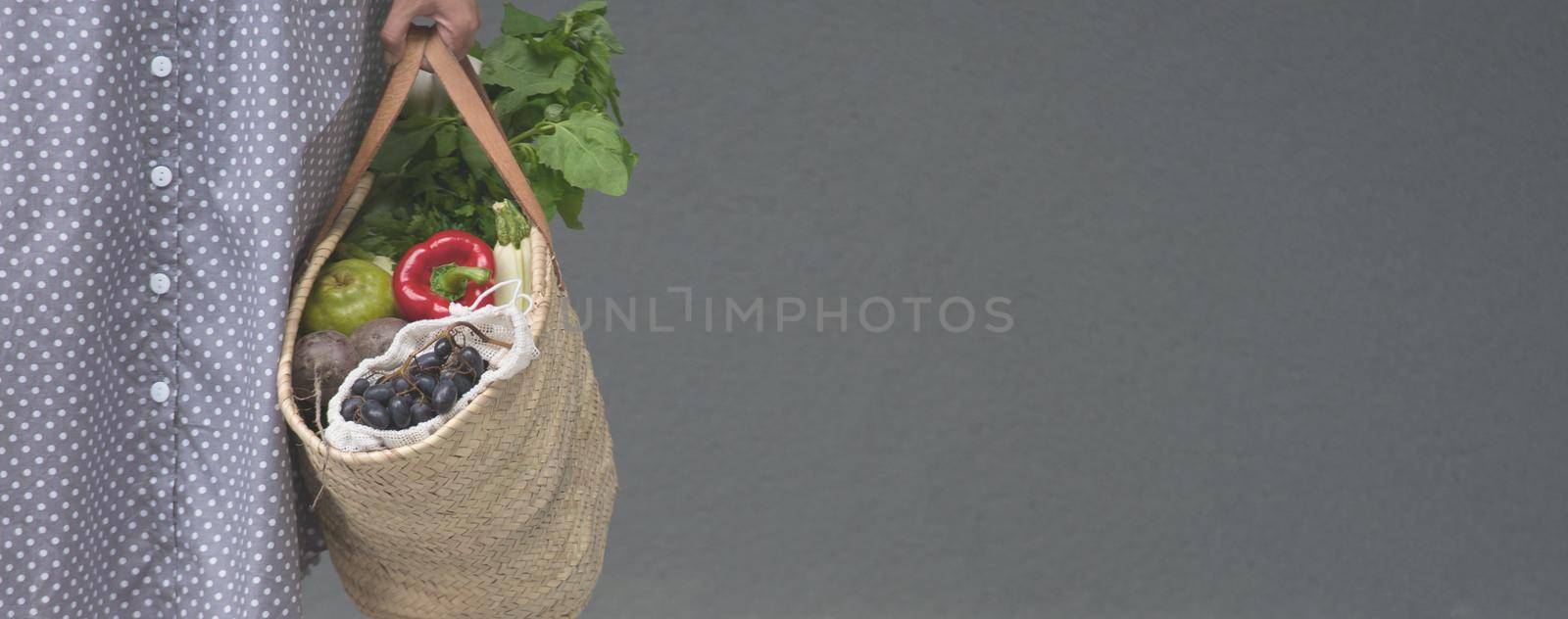 woman is holding straw back for shopping with products without plastic packaging. minimalistic concept