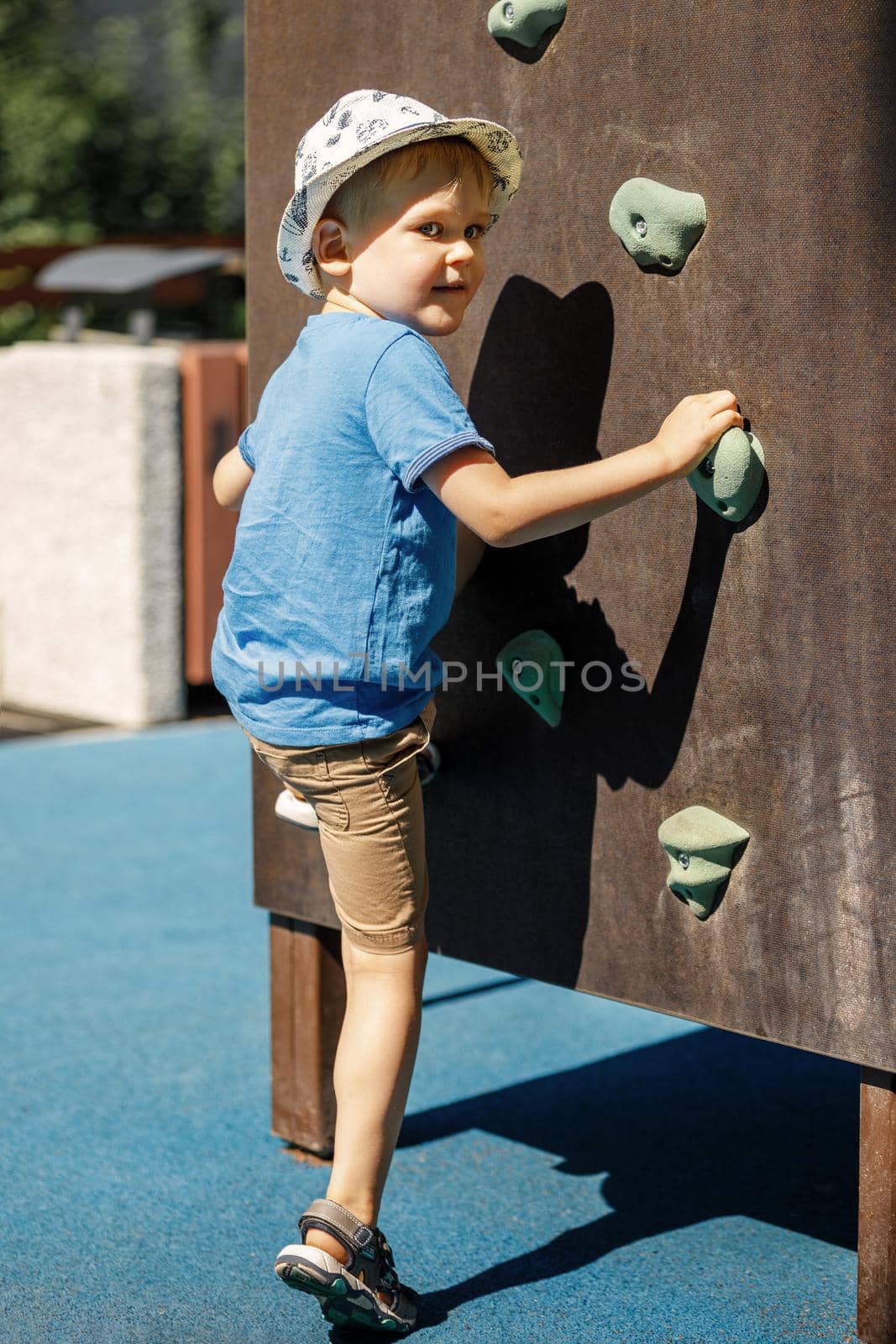 Little boy and climbing wall at playground by Lincikas