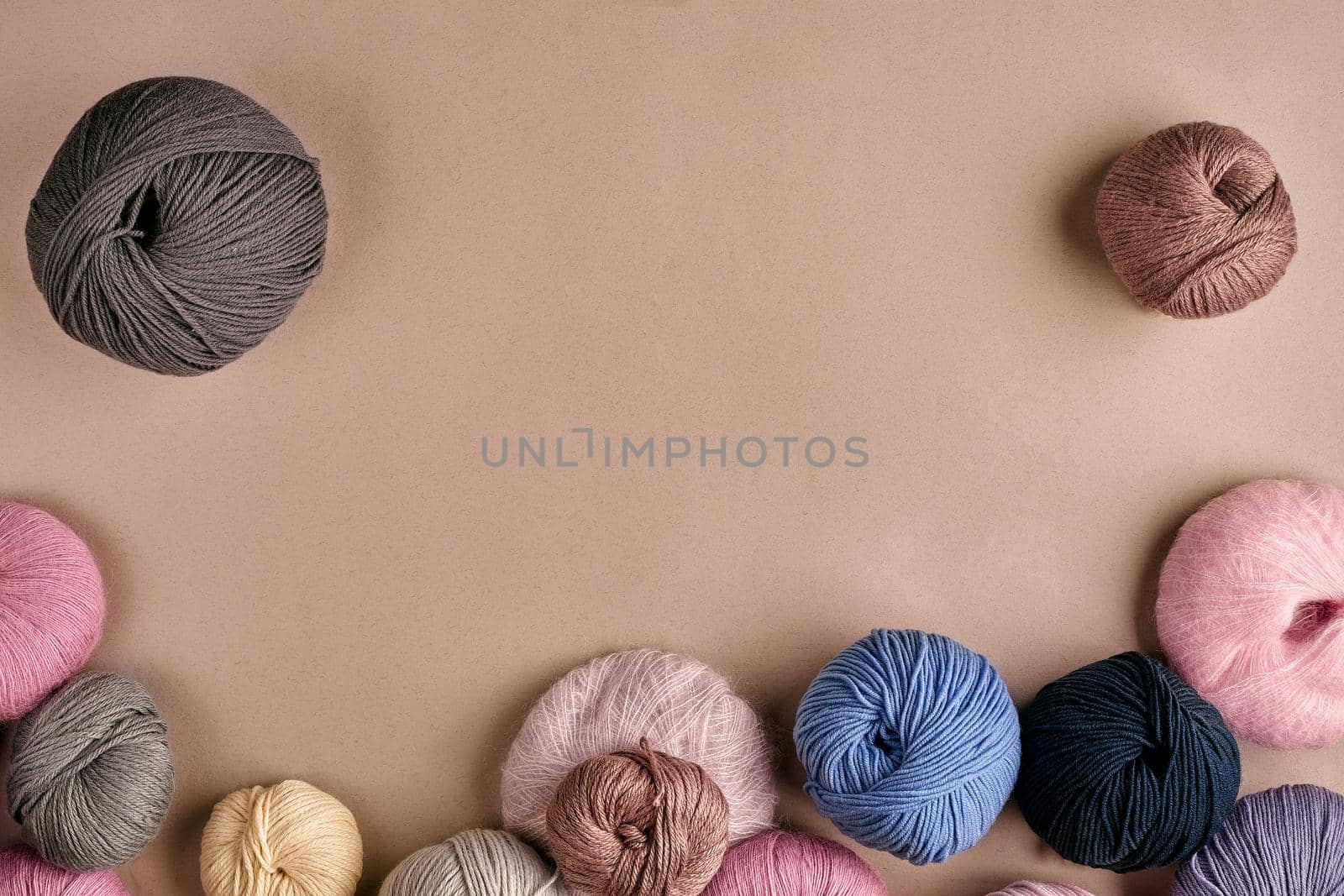 Set of colorful wool yarn on beige background. Knitting as a kind of needlework. Colorful balls of yarn and knitting needles. Top view. Still life. Copy space. Flat lay