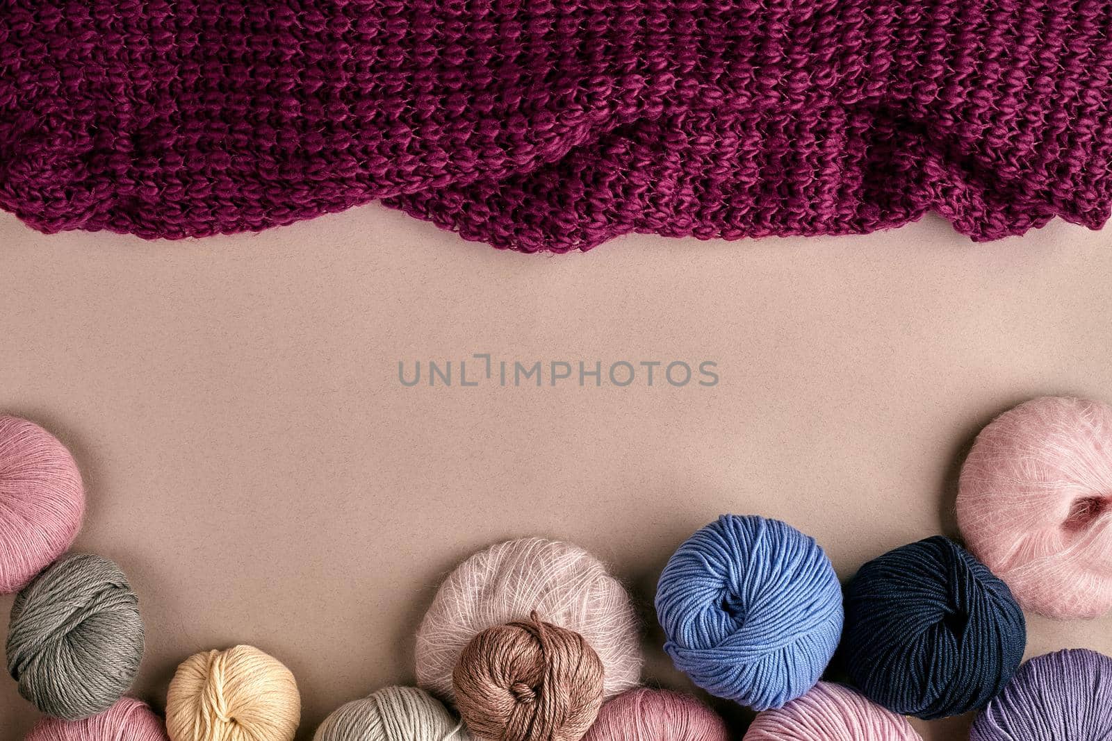 Set of colorful wool yarn on beige background. Knitting as a kind of needlework. Colorful balls of yarn and knitting needles. Top view. Still life. Copy space. Flat lay