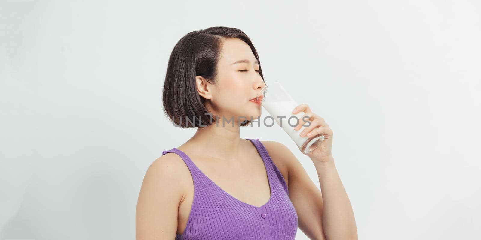 Pregnant woman with glass of milk showing thumb up copy space.