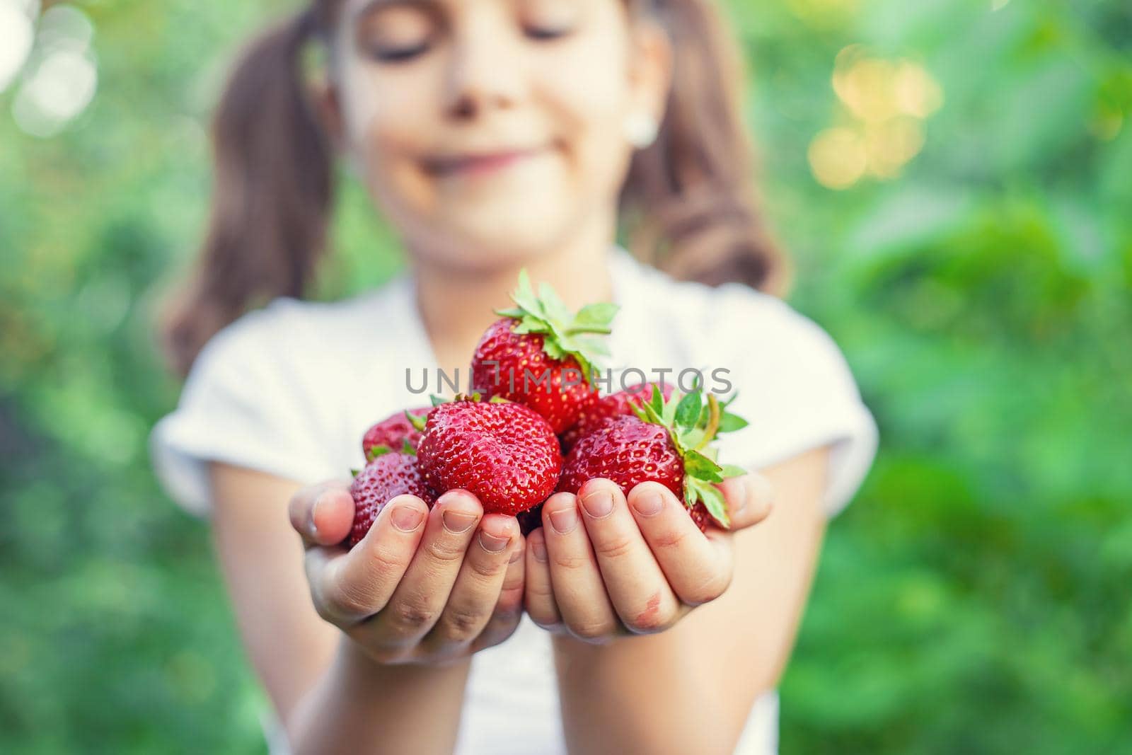 A child with strawberries in the hands. Selective focus. food.
