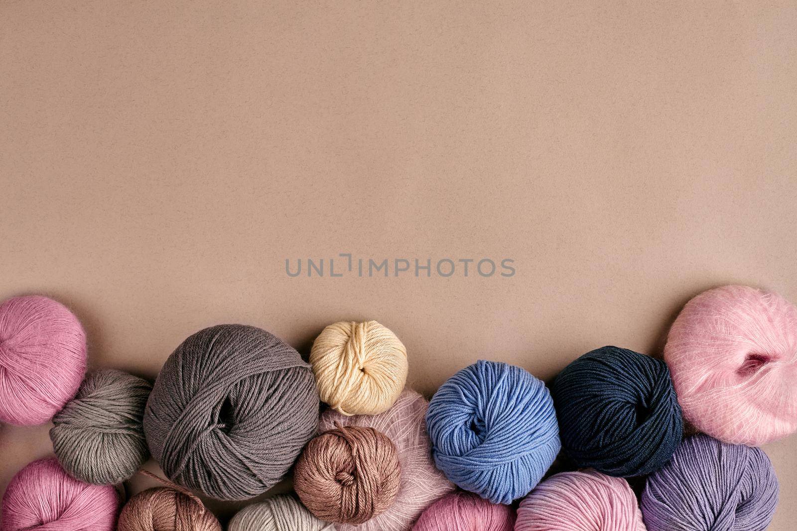 Set of colorful wool yarn on beige background. Knitting as a kind of needlework. Colorful balls of yarn and knitting needles. Top view. Still life. Copy space. Flat lay