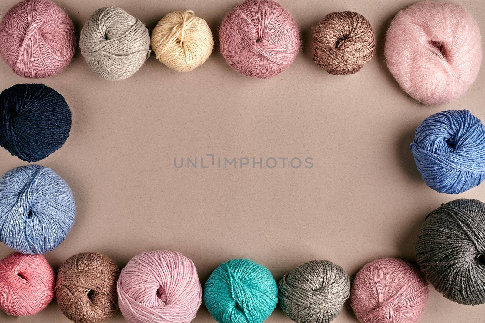 Set of colorful wool yarn on beige background. Knitting as a kind of needlework. Colorful balls of yarn and knitting needles. Top view. Still life. Copy space. Flat lay. Frame of tangles of knitting threads
