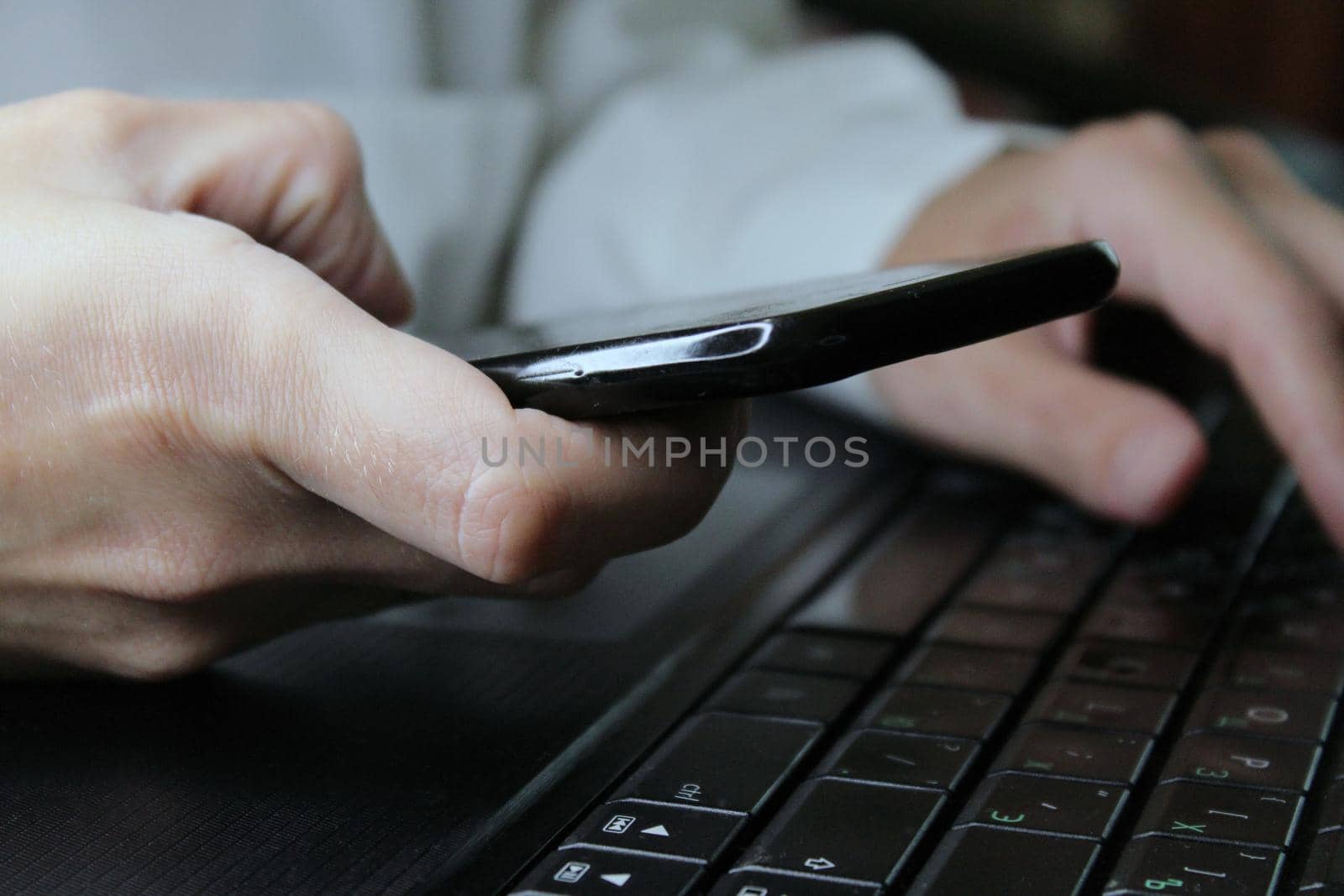 The girl sits at a laptop and holds a smartphone in her hands. Online Shopping. Business concept. .