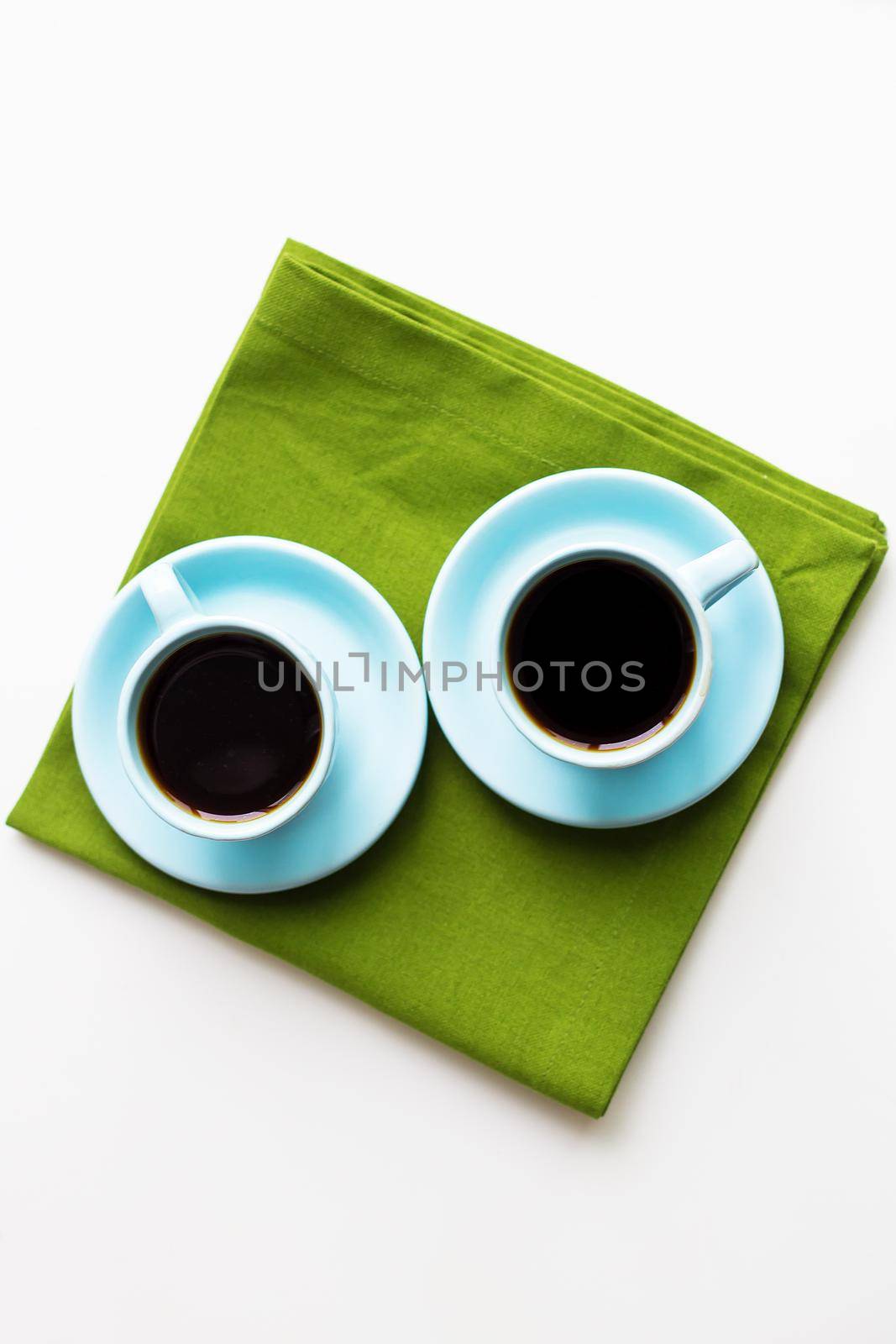 two blue cups of coffee on a table with green cloth