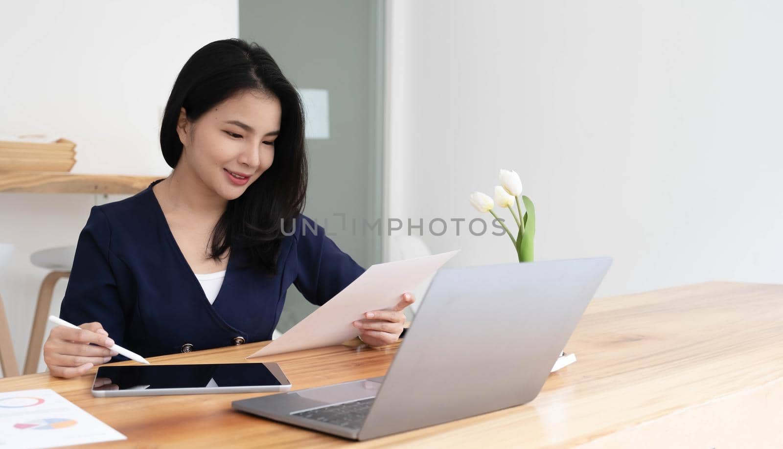 Young asian businesswoman works on tablet with laptop at the office..