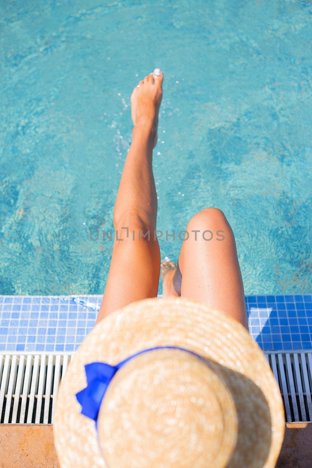 Beautiful girl in a hat near a blue pool - sun, summer, heat. Top view.