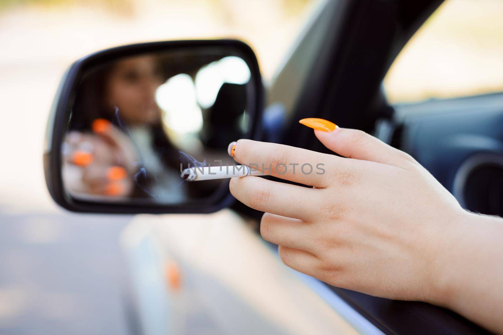 Female hand with cigarette through the window of a car