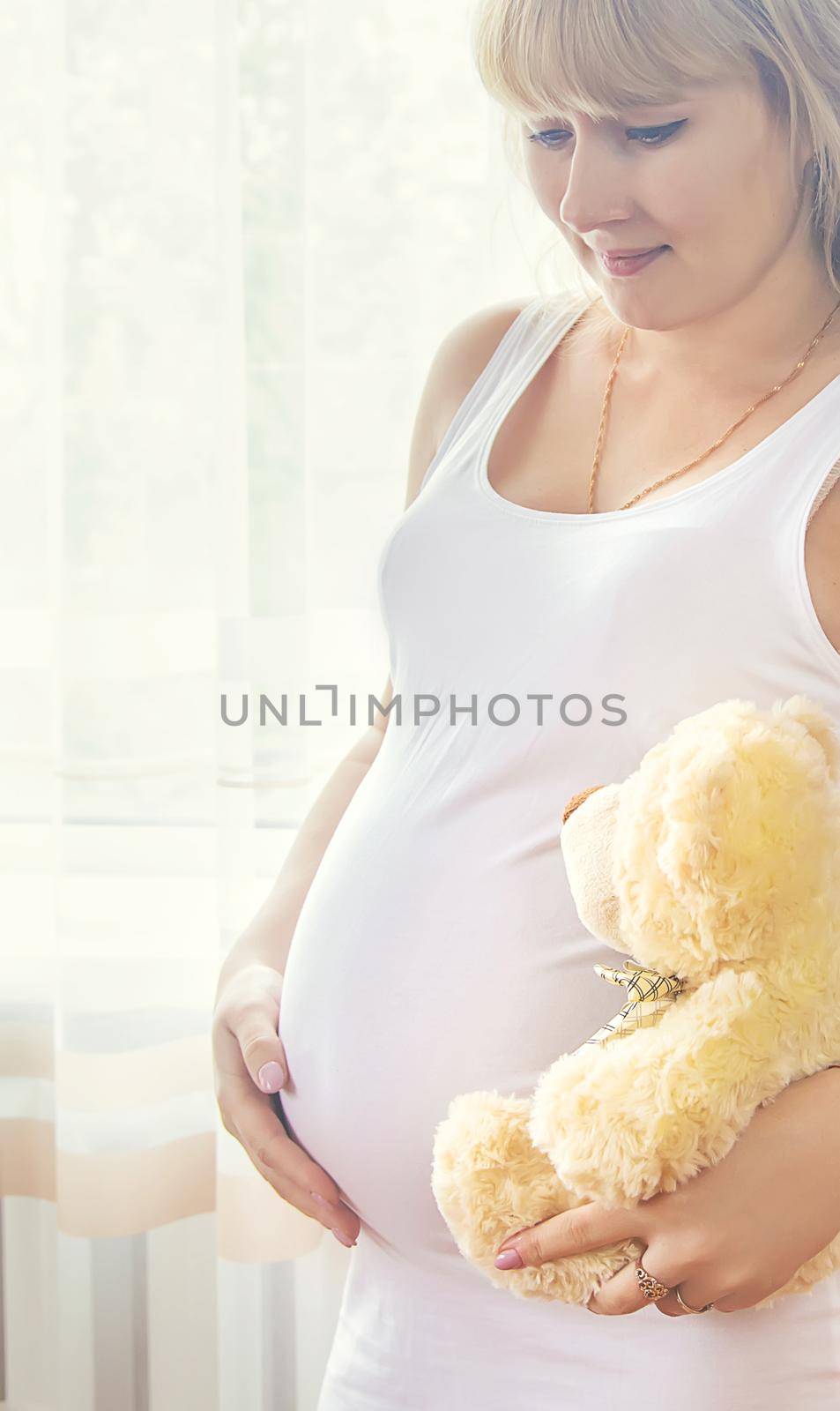 A pregnant woman with a toy hugs her stomach. Selective focus. People.