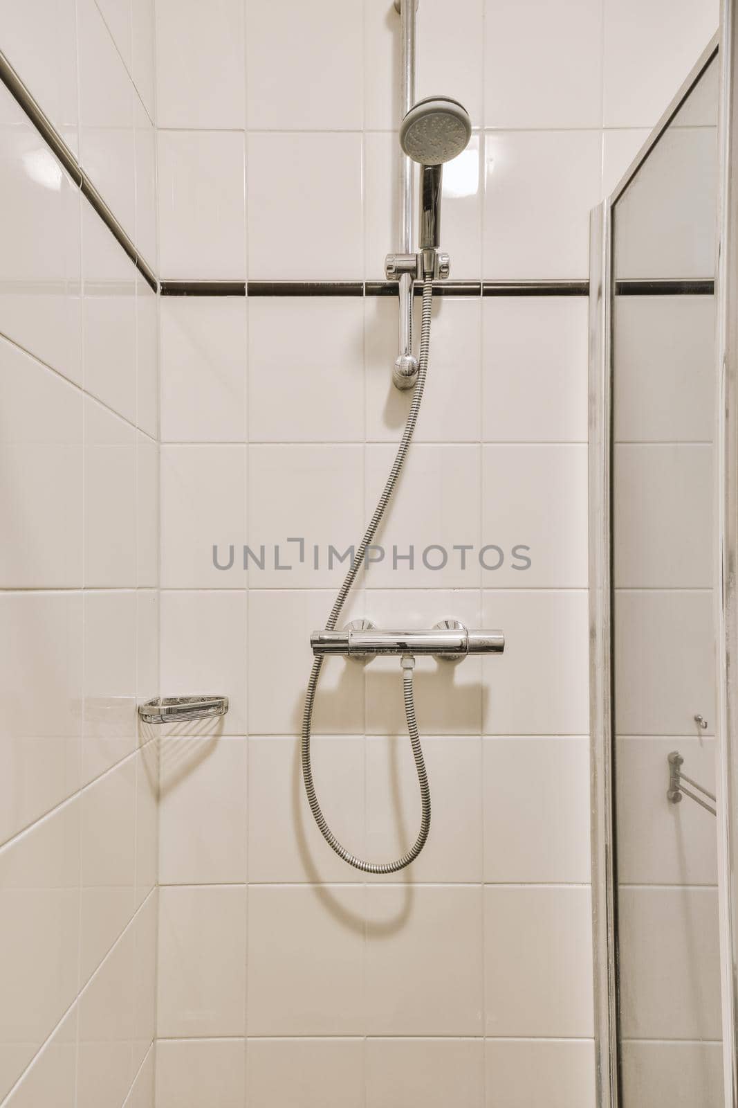 Bathtub with glass shower placed in corner near sink and toilet in small light bathroom with white tile walls