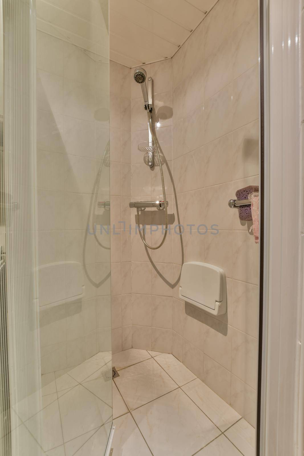 Flush toilet located between sink and shower in small tiled bathroom of contemporary apartment