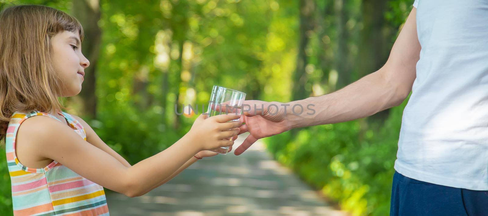 The father gives the child a glass of fresh water. Selective focus. nature.