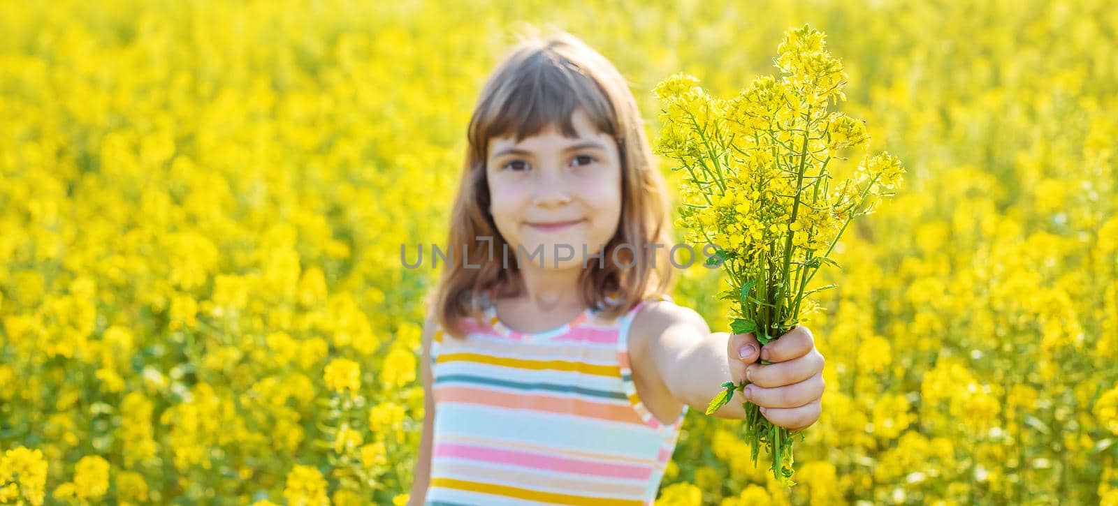 A child in a yellow field, mustard blooms. Selective focus.