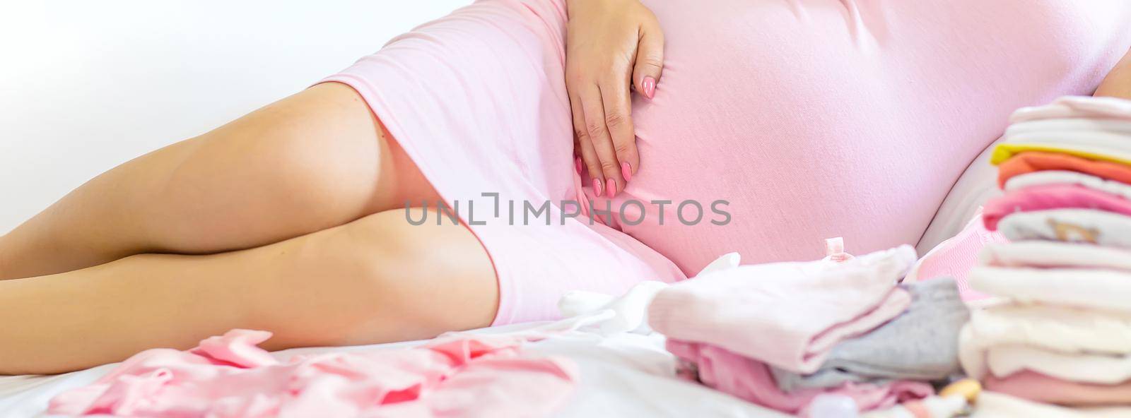 A pregnant woman is folding baby things. Selective focus. people.