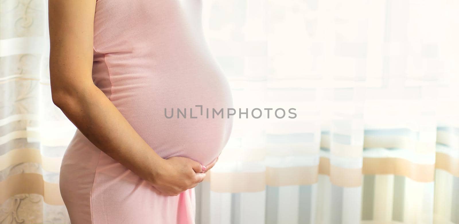A pregnant woman in bed hugs her stomach. Selective focus. people.