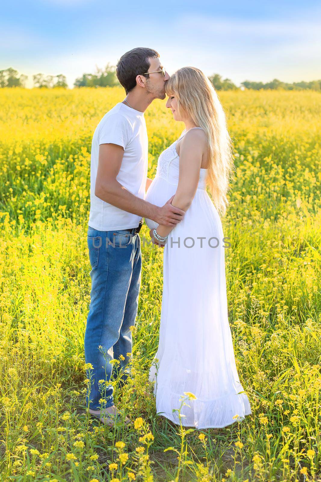 Pregnant woman and man photo shoot in mustard field. Selective focus. by yanadjana