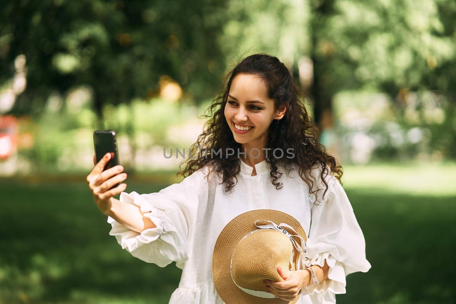 Young beautiful girl in a hat makes a selfie on her phone in the park. High quality photo