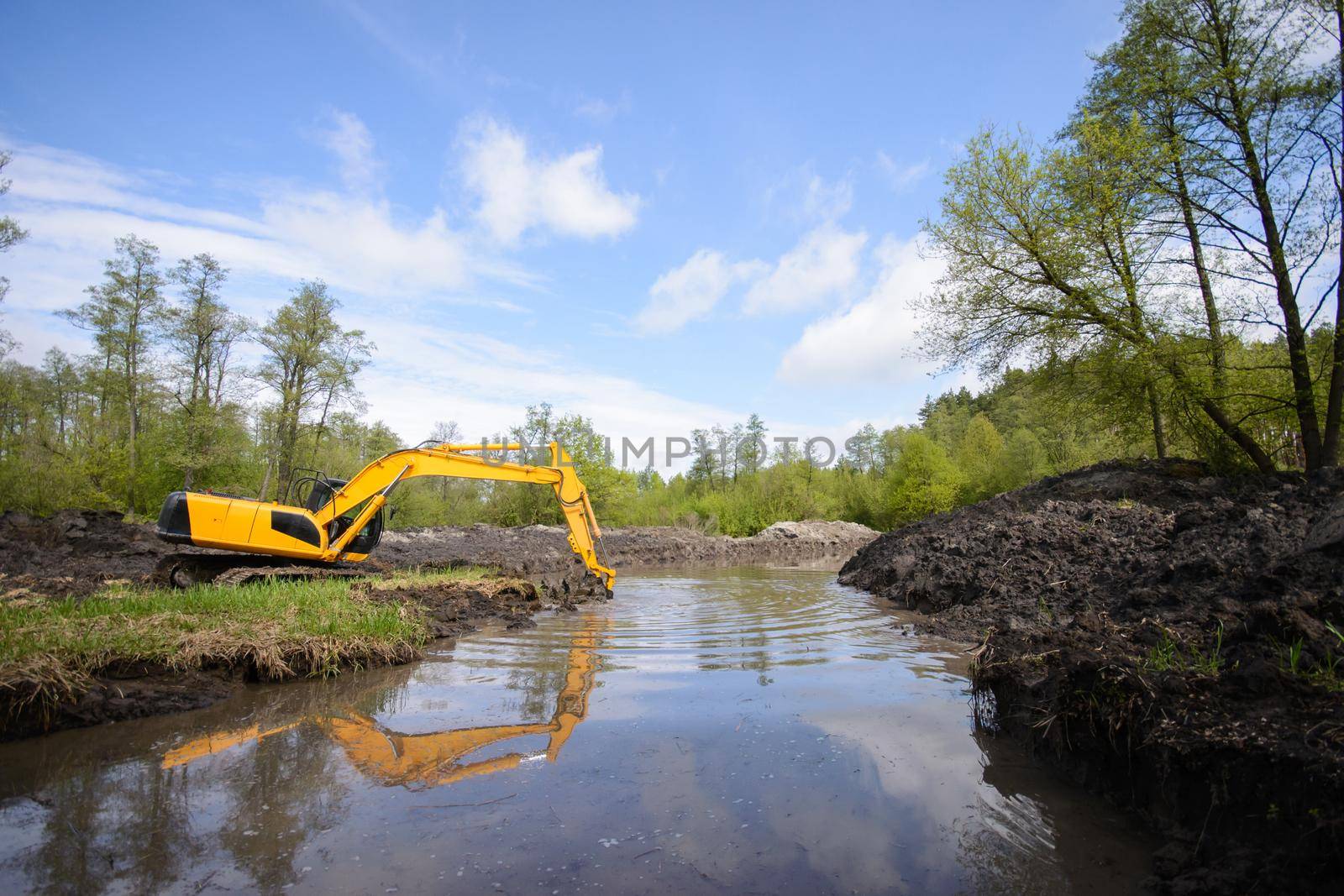 Countryside view of a drainage canal system and working excavator