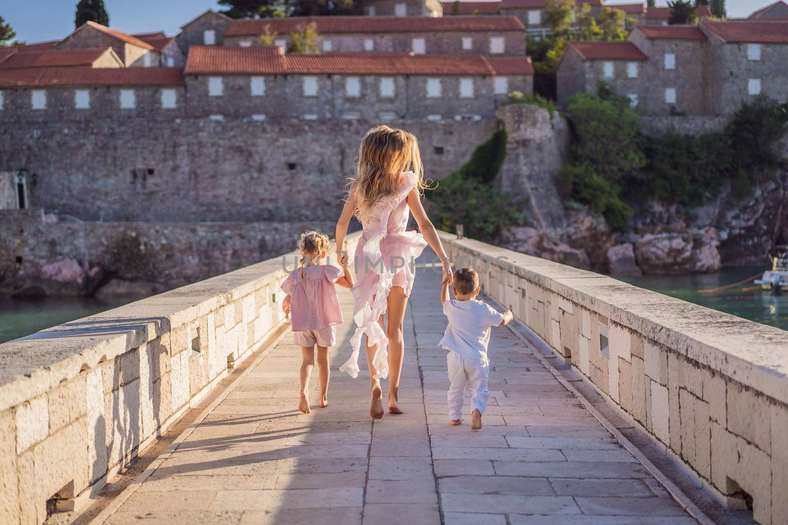 Mother and two children daughter and son tourists on background of beautiful view St. Stephen island, Sveti Stefan on the Budva Riviera, Budva, Montenegro. Travel to Montenegro concept by galitskaya