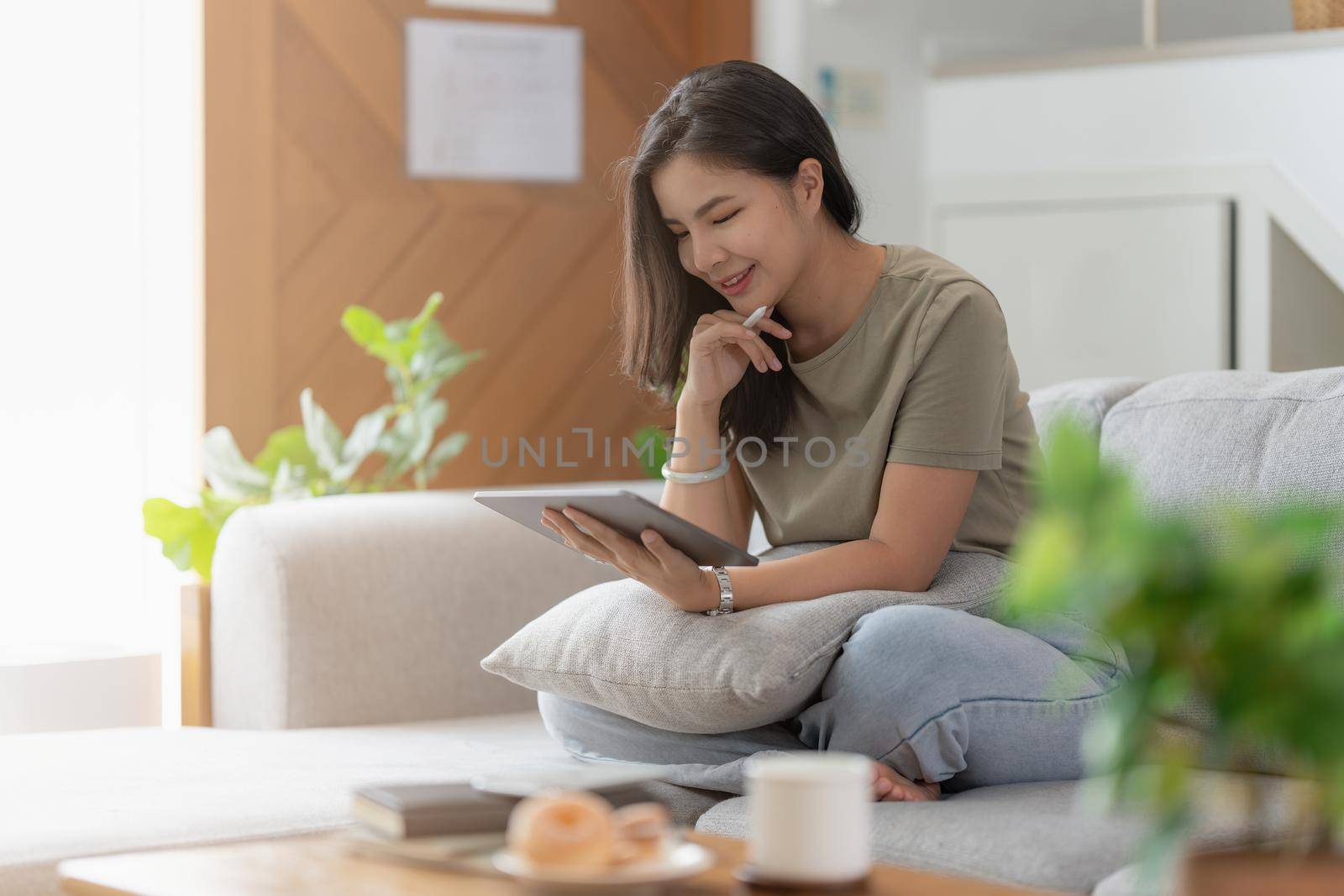 Portrait of Young Asian woman using social media for chatting by digital tablet. Lifestyle ,Shopping online, relax on sofa