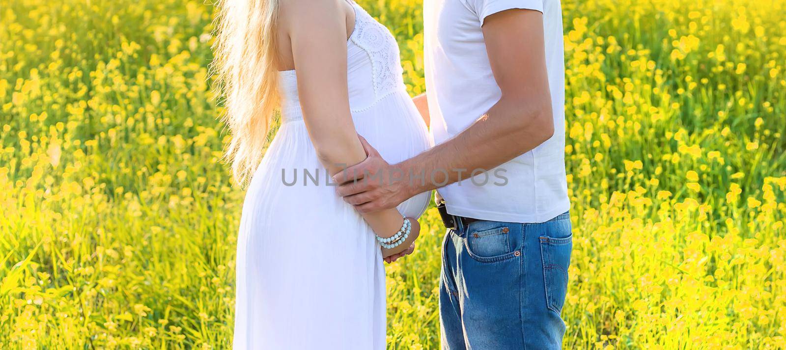 Pregnant woman and man photo shoot in mustard field. Selective focus. by yanadjana