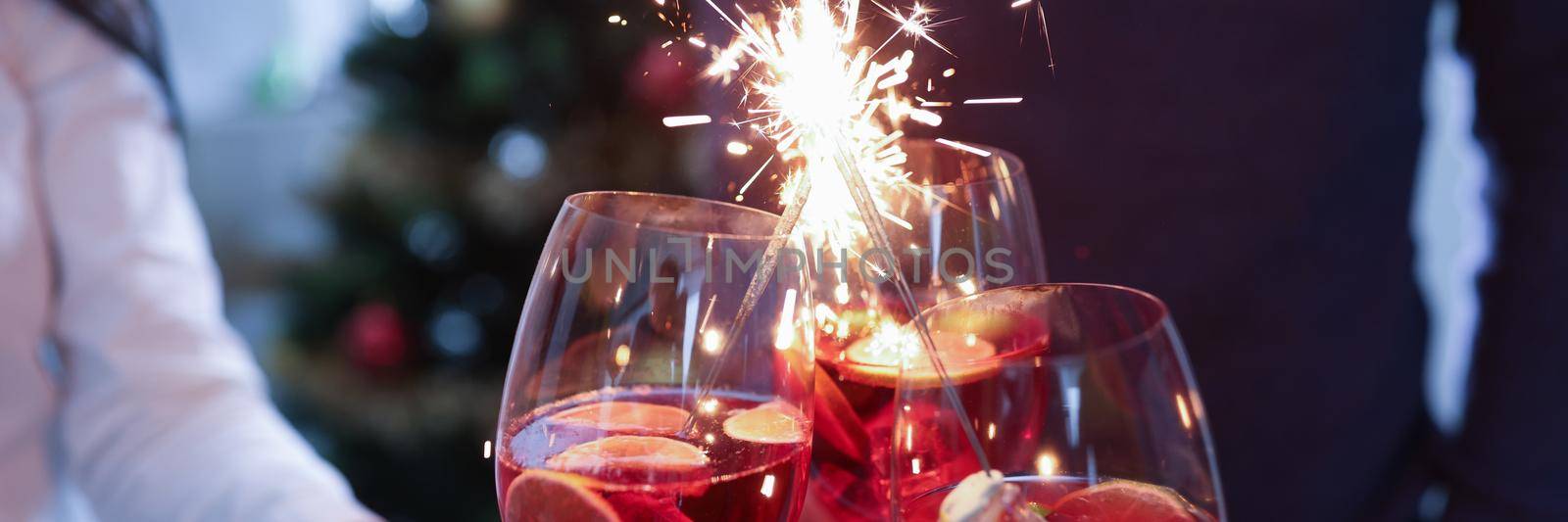Group of people clinking glasses with alcoholic cocktail and sparklers closeup by kuprevich