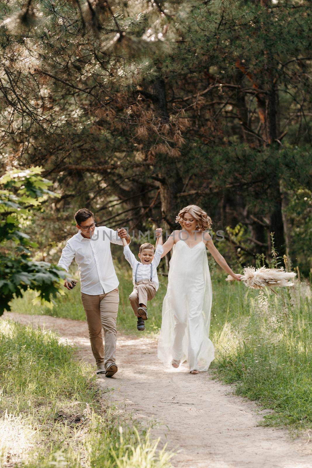 happy family three dad mom and son on a walk in the woods