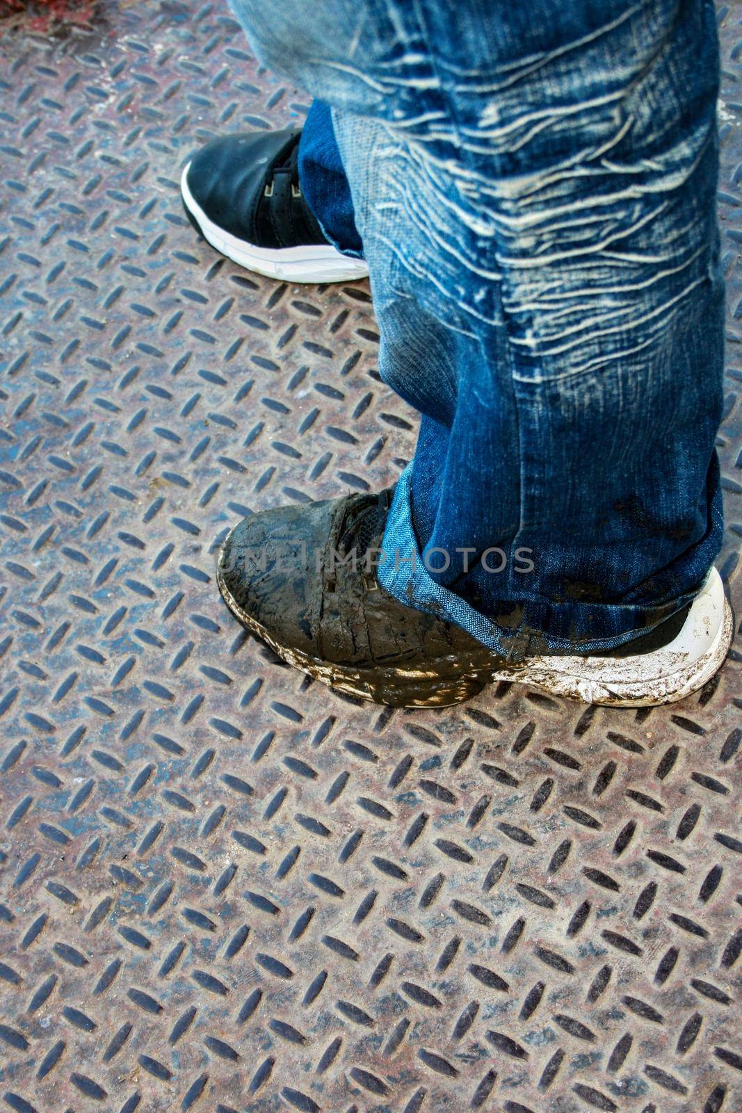 Photo of a dirty pair of tennis shoes and the bottom of a blue jean
