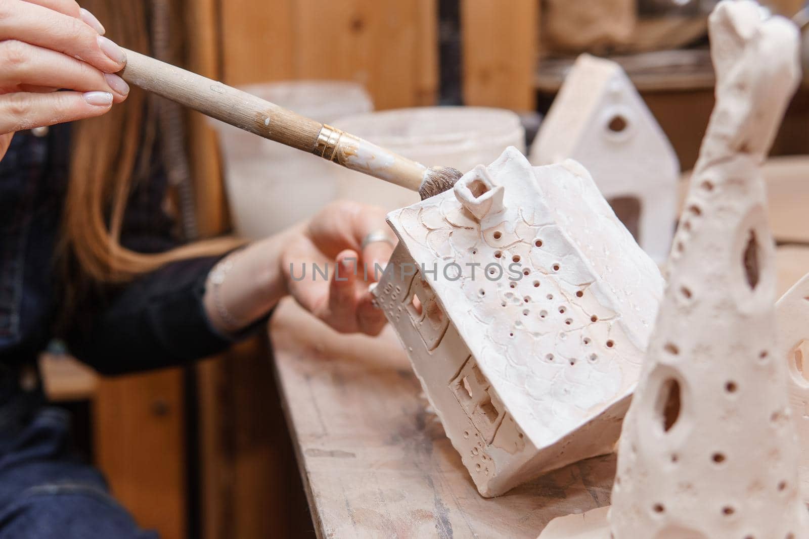 A master ceramist holds a clay product in his hands. Making a ceramic candle holder from clay. The process of coating the candlestick with glaze. Close-up.