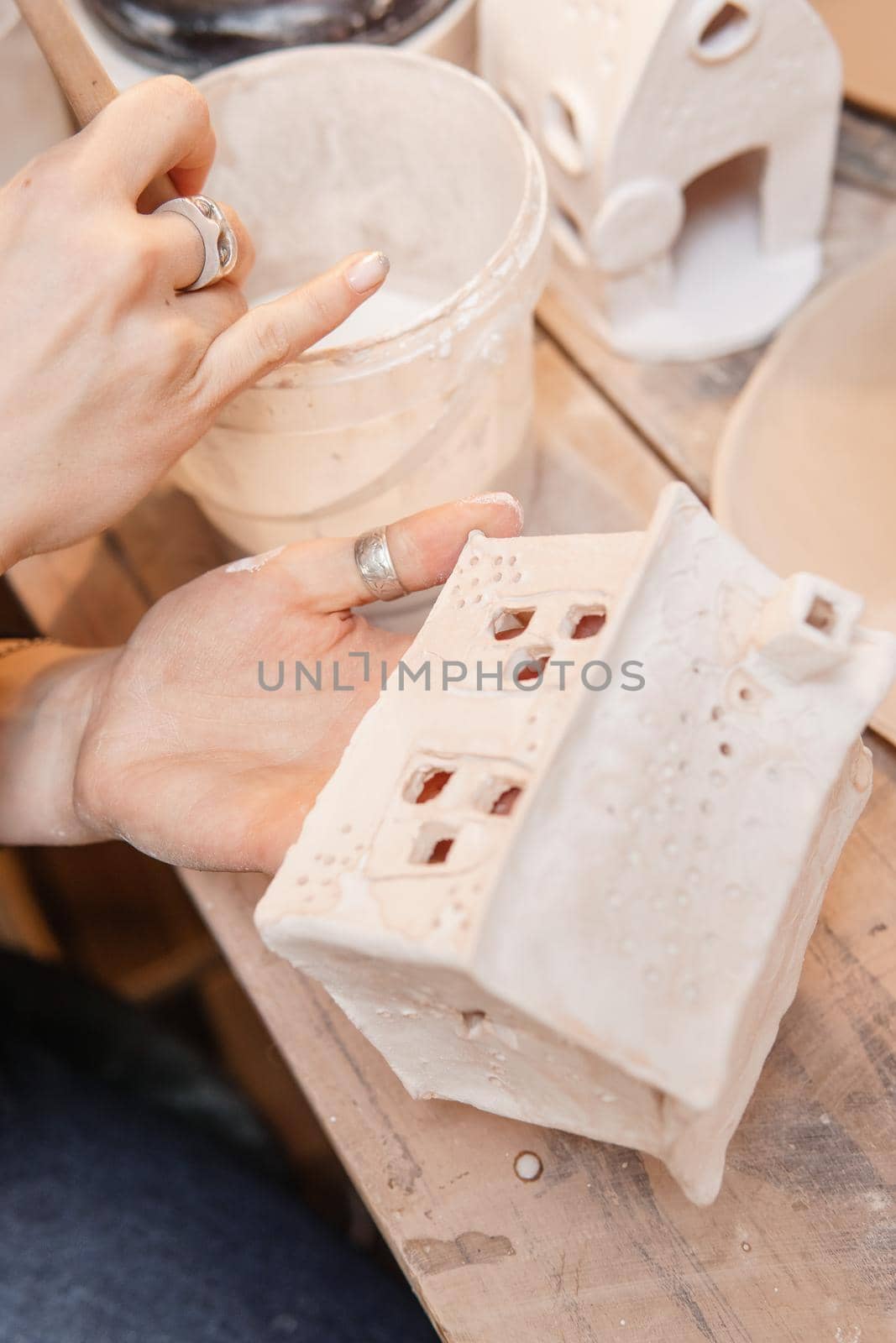 A master ceramist holds a clay product in his hands. Making a ceramic candle holder from clay. The process of coating the candlestick with glaze. Close-up.
