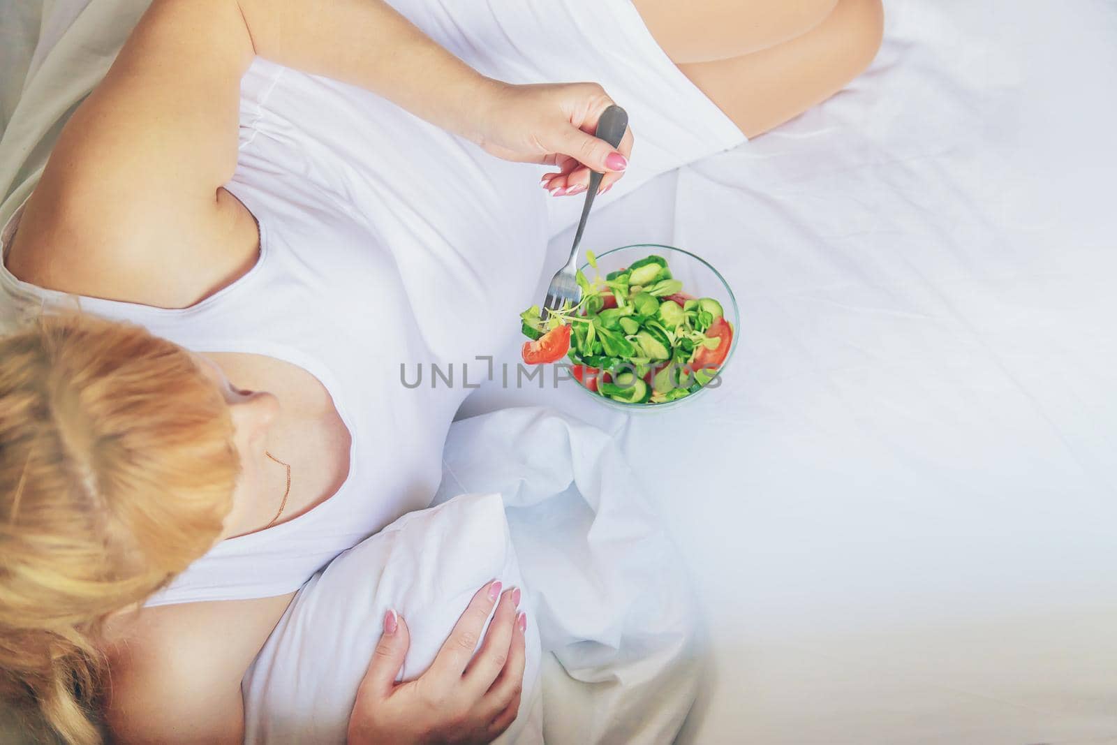 A pregnant woman eats a salad with vegetables. Selective focus. Food.