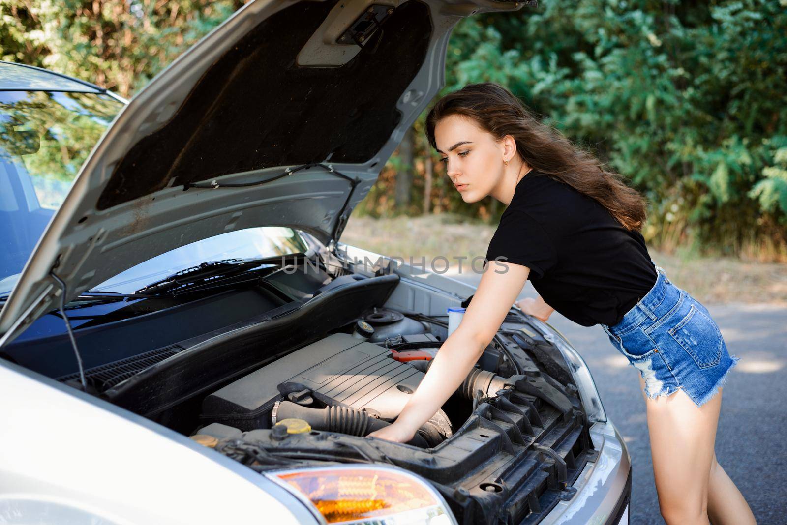 Young woman checks car engine by VitaliiPetrushenko