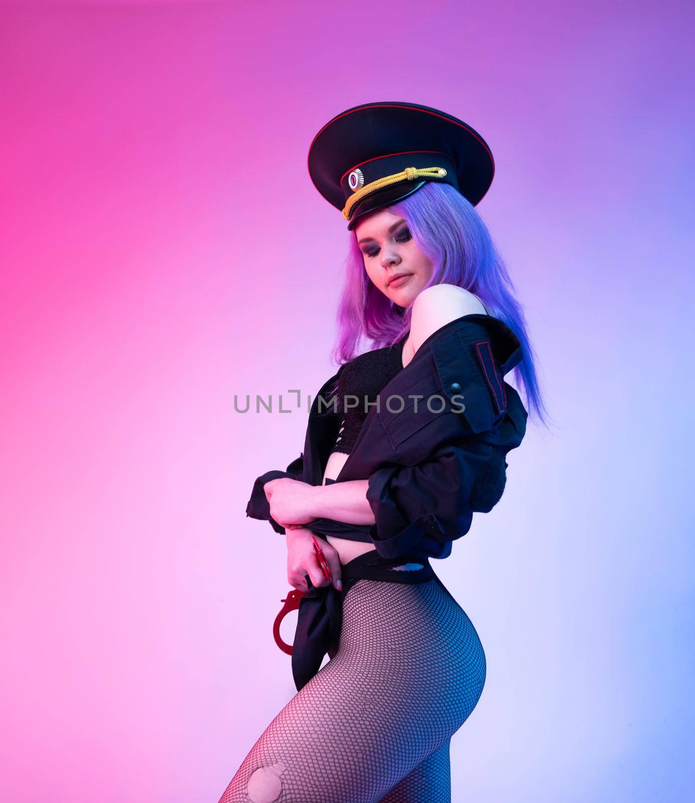 the Sexy girl in police uniform posing in underwear with handcuffs in neon light