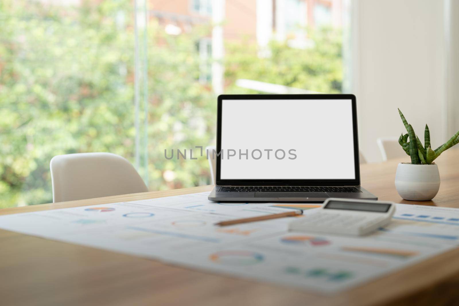 modern laptop computer with blank screen at workplace in office. finance report and calculator accounting on wooden table.