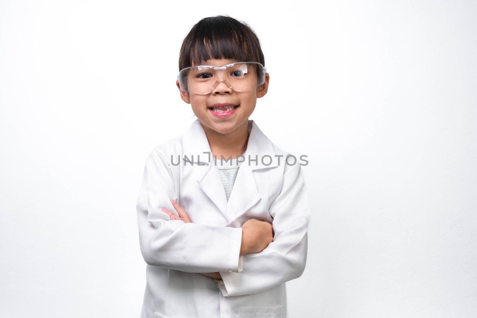 Portrait of a smiling little girl with glasses standing with her arms crossed in a doctor or science suit on a white background. Little scientist.