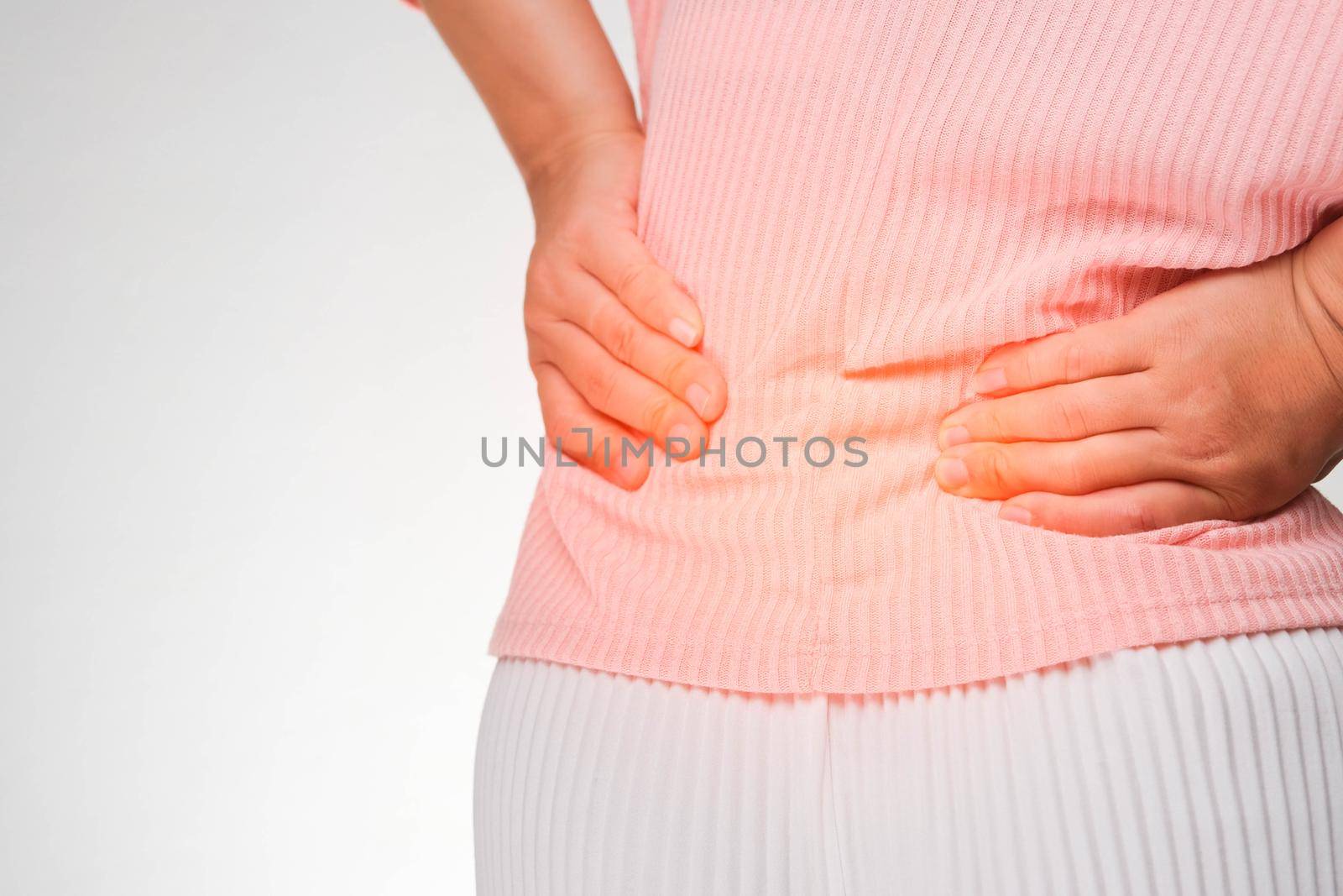 Back view of woman suffering from backache, waist pain, muscle or chronic nerve pain in her back after working. close up. Health problems, concepts of diseases of the musculoskeletal system.