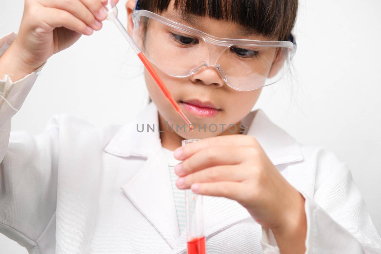Little scientist. Smiling little girl learning classroom in school lab holding test tubes. Little girl playing science experiment for home schooling. by TEERASAK