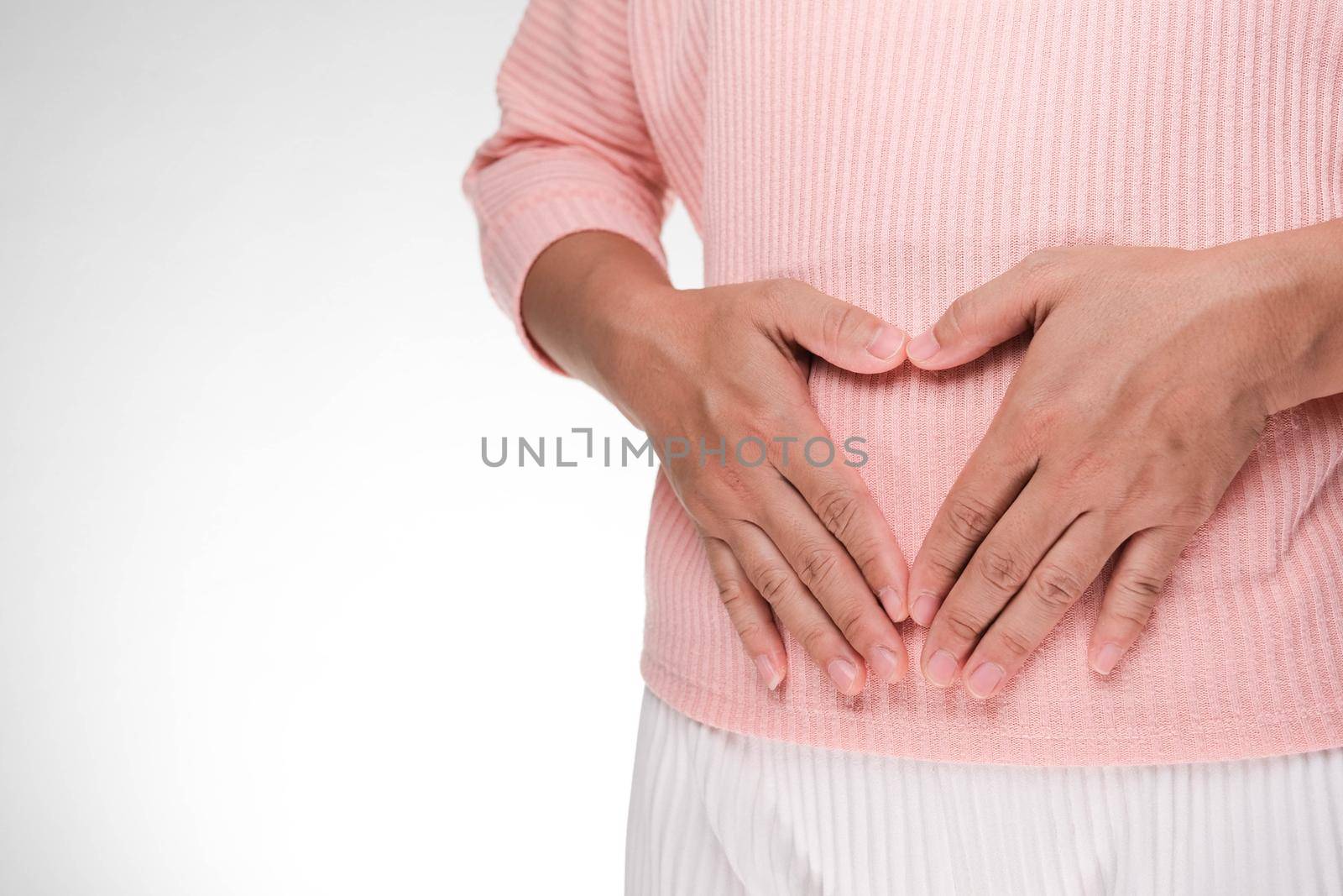 Close up of woman's hands made heart on belly isolated on white background. Young woman holding hands near belly. Early pregnant concept. by TEERASAK